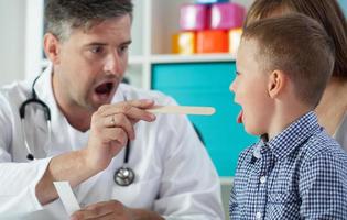il pediatra esamina la gola del ragazzo foto