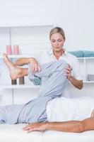 Fisioterapista che fa massaggio alle gambe al suo paziente foto