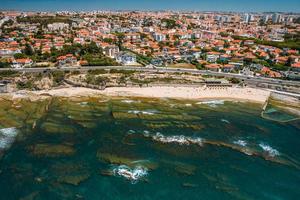 vista aerea del drone della spiaggia di avencas con il quartiere delle parate nella grande lisbona, in portogallo foto