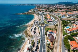 Vista aerea del drone della costa che abbraccia il viale marginale con il distretto di sao pedro de estoril nella grande lisbona, portogallo foto