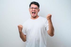 giovane uomo asiatico che indossa una camicia casual in piedi molto felice ed eccitato facendo il gesto del vincitore con le braccia alzate, sorridente e urlando per il successo. concetto di celebrazione foto