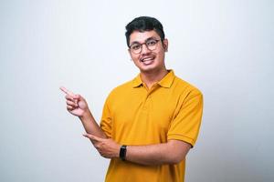 uomo asiatico che indossa una camicia casual su sfondo bianco con un grande sorriso sul viso, puntando con il dito della mano di lato guardando la telecamera. foto