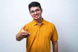 giovane asiatico che indossa abiti casual sorridente amichevole offrendo stretta di mano come saluto e benvenuto foto