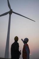 ingegneri accanto a una turbina eolica al tramonto
