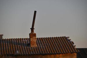 un camino di ferro storto in un vecchio fienile la sera sotto i raggi del sole. foto