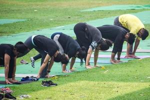 nuova delhi, india, 18 giugno 2022 - lezione di yoga di gruppo surya namaskar per persone di età diverse nel giardino di lodhi, giornata internazionale di yoga, grande gruppo di adulti che frequentano una lezione di yoga nel parco foto