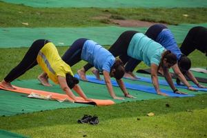 nuova delhi, india, 18 giugno 2022 - lezione di yoga di gruppo surya namaskar per persone di età diverse nel giardino di lodhi, giornata internazionale di yoga, grande gruppo di adulti che frequentano una lezione di yoga nel parco foto