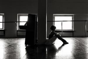 un'affascinante ballerina in body posa elementi di balletto in un copricapo in uno studio fotografico foto