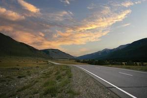 nastro di strada tra le pendici dei monti sulle distese di altai in una giornata estiva foto