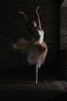 un'affascinante ballerina in body posa elementi di balletto in un copricapo in uno studio fotografico foto