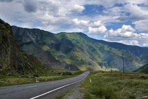 nastro di strada tra le pendici dei monti sulle distese di altai in una giornata estiva foto