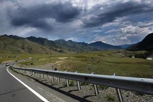 nastro di strada tra le pendici dei monti sulle distese di altai in una giornata estiva foto