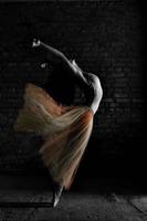 un'affascinante ballerina in body posa elementi di balletto in un copricapo in uno studio fotografico foto