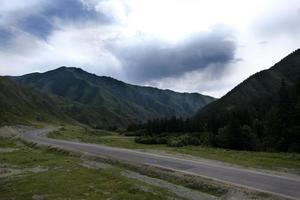 nastro di strada tra le pendici dei monti sulle distese di altai in una giornata estiva foto