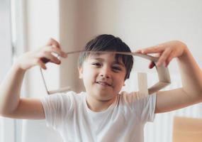 ragazzo felice che usa cartone per le cuffie, bambino attivo con un grande sorriso mentre gioca a cardbox, bambino positivo che si rilassa a casa nel fine settimana, idea di giocattoli fai da te per i bambini foto