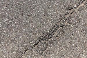 una strada asfaltata con molte buche e danni foto