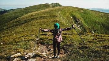 turista donna sta camminando su un sentiero escursionistico sullo sfondo di montagne verdi foto