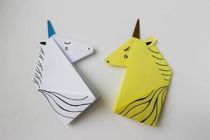 unicorni bianchi e gialli realizzati con la tecnica dell'origami su sfondo bianco. foto