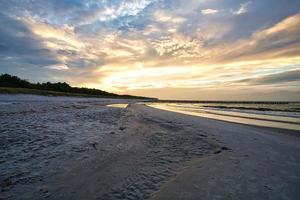 tramonto sulla costa baltica con nuvole nel cielo e riflessi nell'acqua. foto