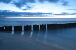 tramonto sulla spiaggia del mar baltico. i pennelli raggiungono il mare. ora blu foto