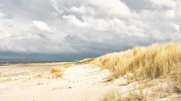 sulla spiaggia del mar baltico con nuvole, dune e spiaggia. escursionismo in autunno. foto