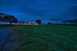 strada con alberi e prati all'ora blu la sera foto