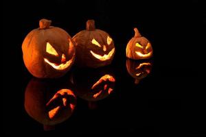 zucca di Halloween con candele accese su sfondo nero foto