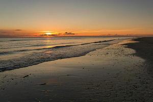 tramonto sulla spiaggia di blavand in danimarca. camminando la sera in un'atmosfera di grande luce foto