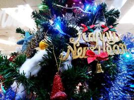 decorazione verde dell'albero di natale e felice anno nuovo con luce blu, campana dorata e palla. foto