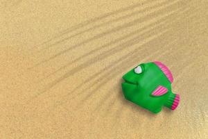 rabboccare la vista del pesce di gomma verde sulla spiaggia di sabbia. sfondo del concetto di vacanza. foto