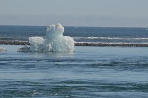 vista mozzafiato di un iceberg unico con sabbia nera sullo sfondo foto