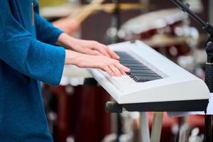 musicista donna che suona sul pianoforte della tastiera del sintetizzatore, le mani premono i tasti del sintetizzatore sul palco del concerto foto