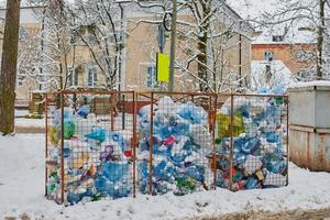 tre cassonetti pieni di bottiglie di plastica, sacchi e rifiuti foto