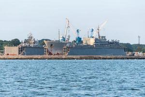 grandi navi della marina di ferro in cantiere per la riparazione. grande gru in cantiere. porto di mare blu foto