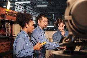 i team di ingegneri del settore professionisti multirazziali in uniformi di sicurezza lavorano ispezionando la corrente di tensione delle macchine, controllando e mantenendo presso la fabbrica di produzione, le occupazioni dei servizi di sistema elettrico. foto