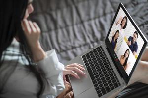 vista posteriore della donna che parla alla chat video con i colleghi utilizzando la webcam del laptop in videoconferenza, riunione online di lavoro intelligente del team aziendale in videochiamata da casa foto