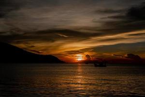 bel tramonto e una barca al mare foto