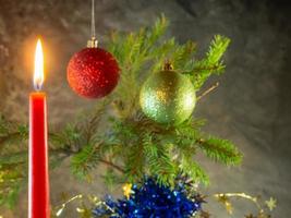 la candela rossa di natale brucia sullo sfondo dei rami di abete. decorazione natalizia. atmosfera di Capodanno. foto