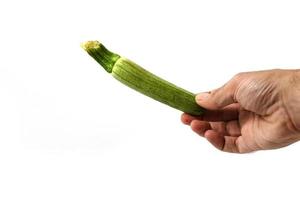 mano che tiene le zucchine su uno sfondo bianco foto