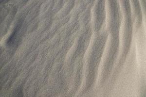 consistenza della sabbia. sfondo strutturato di sabbia ondulata. spiaggia di sabbia strutturata foto