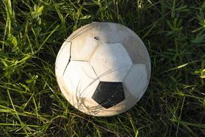 un vecchio pallone da calcio giace nell'erba, primo piano foto