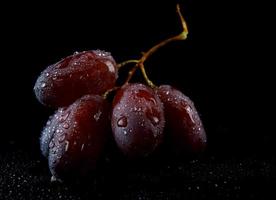 diversi acini d'uva succosi sono isolati su uno sfondo nero. foto