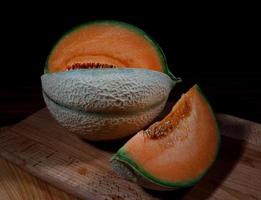 melone maturo e fetta di melone su una tavola di legno. foto