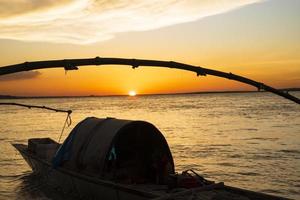 una barca di legno sul mare contro il cielo durante il tramonto foto