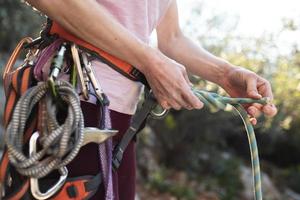 uno scalatore prepara l'attrezzatura per l'arrampicata, la donna tiene una corda, un nodo foto