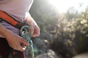 uno scalatore prepara l'attrezzatura per l'arrampicata, la donna tiene una corda, un nodo foto