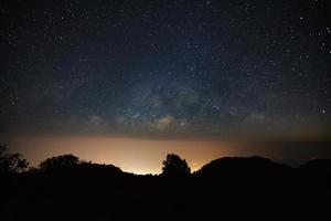 galassia della Via Lattea sopra la montagna con la luce della città e la polvere spaziale nell'universo foto