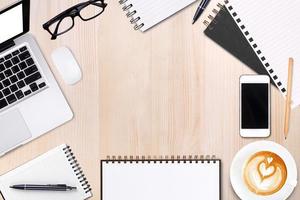 taccuino aperto in bianco con penna, occhiali e telefono cellulare, tazza di caffè latte art su tavola di legno. modello di business mock up per aggiungere il tuo testo. vista dall'alto. foto