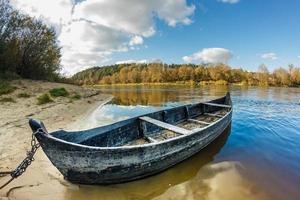 vecchia barca di legno sulla riva di un ampio fiume in una giornata di sole foto