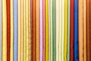 un'ampia selezione di vestiti di tessuti di seta di diversi colori giaceva in fila nel negozio di tendaggi foto
